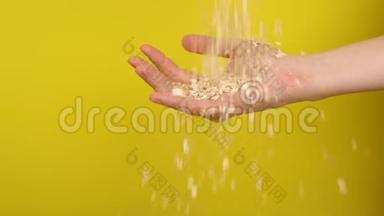 手抓着黄色背景上的燕麦片。